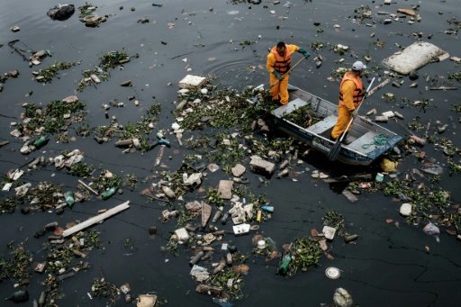 Cleaners clear up debris caught by the "eco-barrier" at Guanabara Bay near to Rio de Janeiro, Brazil, on July 20, 2016. Photo by AFP