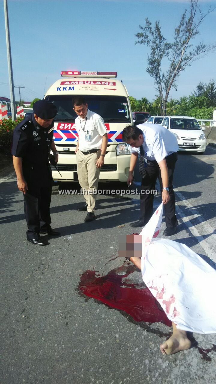 A paramedic from Miri Hospital (right) showing Miri deputy police chief Supt. Stanley Jonathan Ringgit (left) the victim when he arrived at the scene today. 