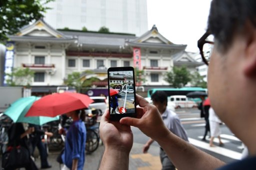 A man plays the Pokemon Go game on his mobile phone in front of the Kabukiza theater in Tokyo. Photo by AFP