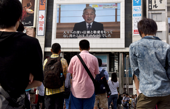 People look at a big video screen on the street as a speech by Japanese Emperor Akihito to the nation is televised in Tokyo. — AFP photo