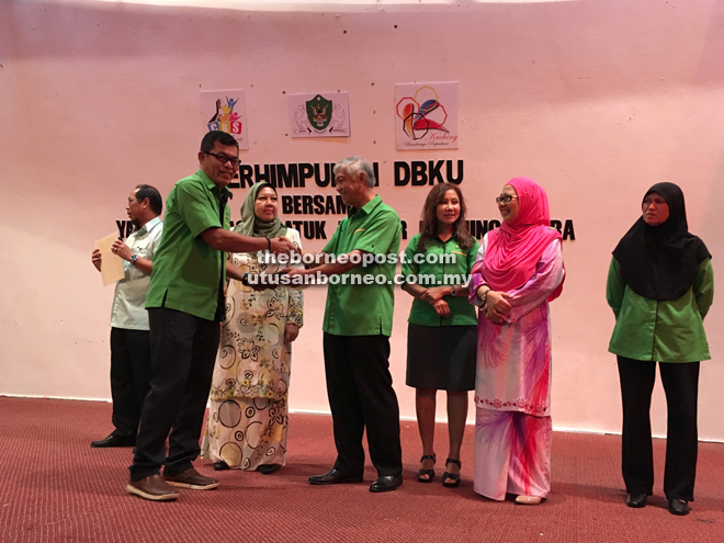 Abang Abdul Wahap (fourth right) presenting the 25-years service award to a recipient as others look on.
