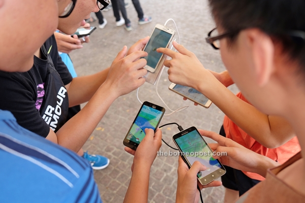 Youths attending the meetup playing Pokemon Go.