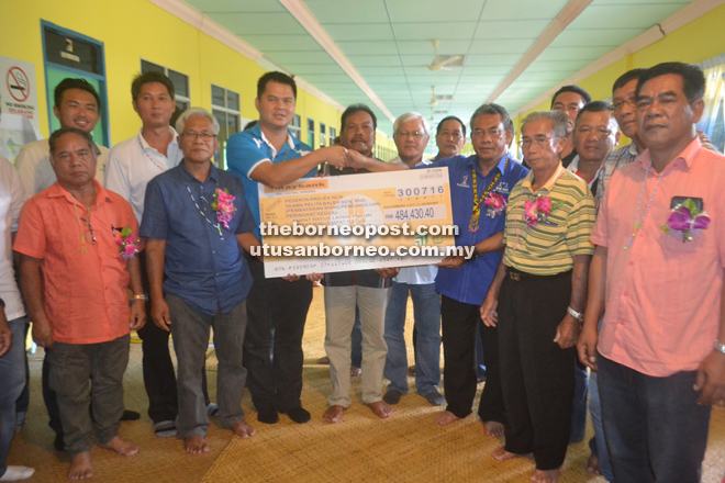 Ta Ann Plantation Sdn Bhd senior general manager Simon Ling Yu Kiong (front row third from left) handing over the mock cheque for the batch 2 of the upfront payment to Nyabong (third from right) while others look on. 