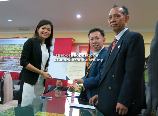 Zee Yeng (left) receives her duly-signed oath of office from Dr Sim as Penguang looks on.  
