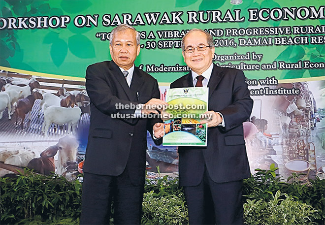 TERIMA KASIH: Uggah menerima cenderamata daripada Dr Ngenang selepas merasmikan Bengkel Program Transformasi Ekonomi Luar Bandar Sarawak di Santubong, semalam. 