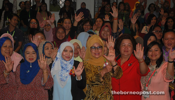 Fatimah (front, third right) and Haliza (second left) join other women in showing their palms that have the word ‘STOP’ written on them – symbolising the call to put a stop on domestic violence.