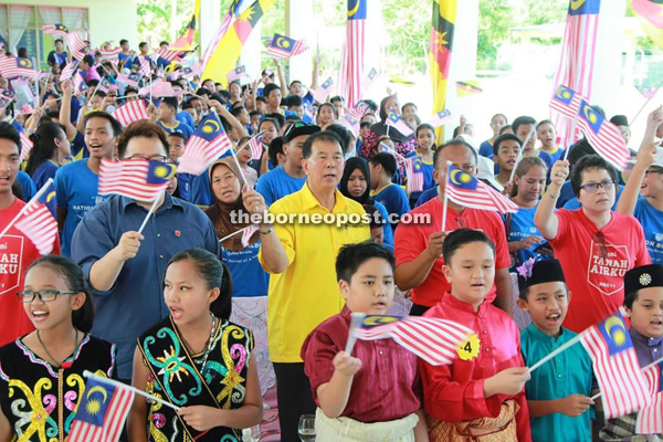 Students of a school in Miri celebrate National Day by waving Jalur Gemilang and state flags. Ting is at centre.