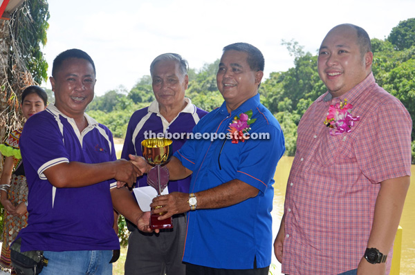 Aaron (second right) presents a trophy to Johan Umpeng (left) who won the first place in the 2.2 horsepower powerboat race. Looking on are Tuai Rumah Benjamin Angki (second left) and Allan (right).