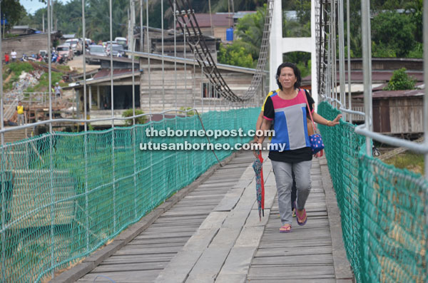 Two women crossing the long-overdue suspension bridge linking SK Saint Matthew with Nanga Sekuau.