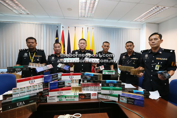 Khaw (third left) and his men show some of the illegal cigarettes seized during the raids on Monday.