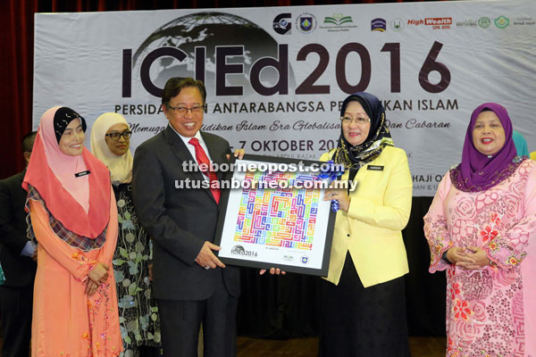 Abang Johari receives a souvenir from Hamsiah after officiating at the conference while Rubiah (right), Noraini (left) and others look on. — Photo by Jeffery Mostapa 