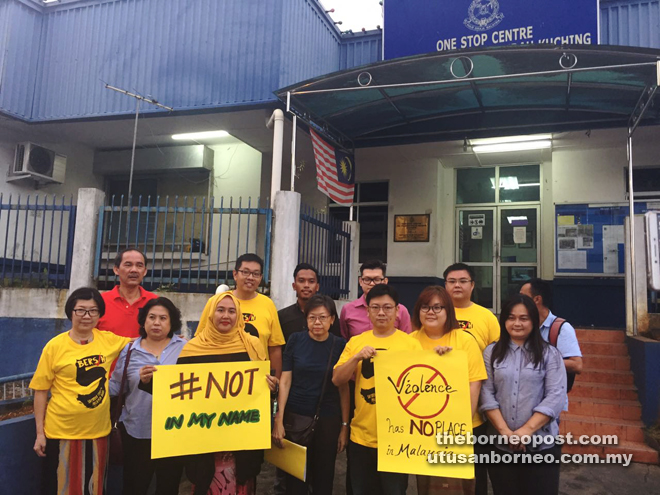 Teo (front row centre) and friends hold placards in front of the police One-Stop Centre prior to lodging her report. 