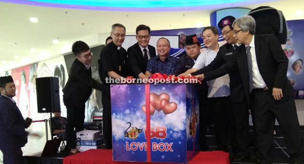 From left: Chew, Rev Lau, Law, Chan, Sim, Chai, Rev Poh and Wong cutting a ribbon on a huge present to release helium filled heart-shaped balloons to launch the event.