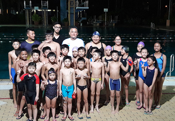 Voon (in white shirt) with his swimming coaches and young swimmers at the Power Aquatic Swimming Club. 