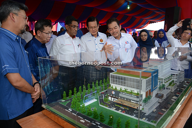 Dr Subramaniam, flanked by Dr Sim on his right and Lee, looking at a model of the proposed hospital.