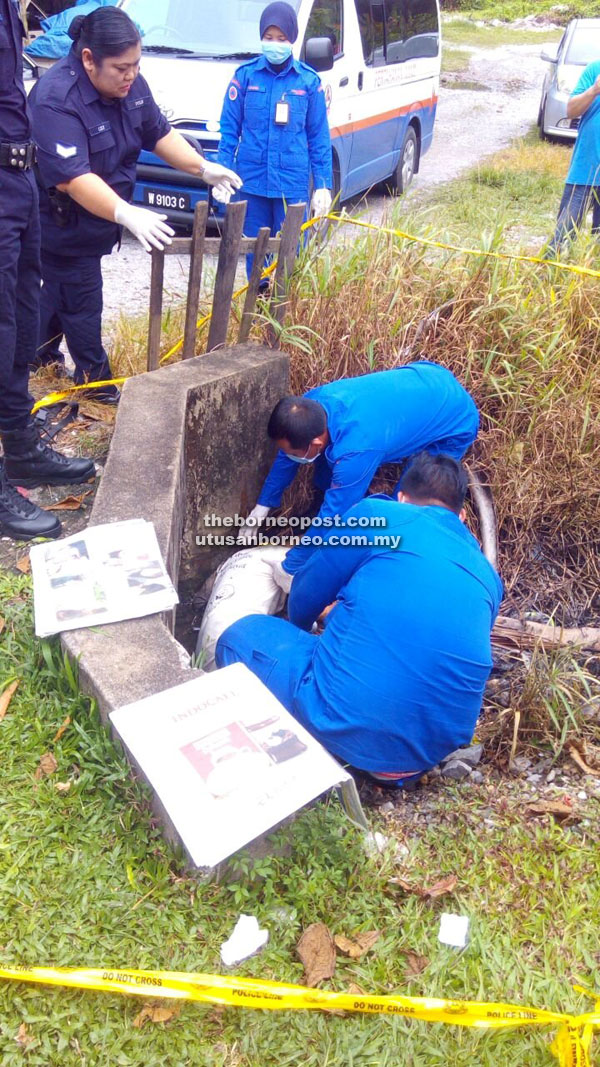 Civil Defence Force personnel attempt to lift Chong Yee from the drain.  