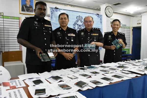 Khoo (second right), Ang (second left) and other officers showing  the seized passports to the media after the press conference. 