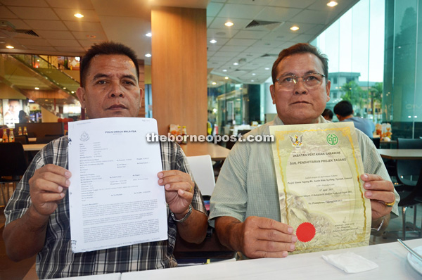 Entili (left) shows the police report while Pengiran is showing the certificate for the association’s Tagang system at Sungai Pang in Ulu Ngemah.