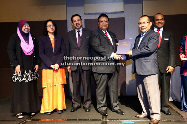 Zainal (fourth left) hands over a certification to a recipient. — Photo by Muhammad Rais Sanusi