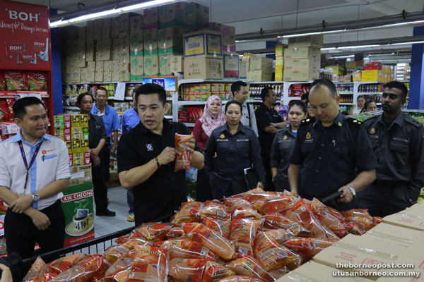 Tan (second left) and Alexander (second right) conducting spot check on the 1kg subsidised cooking oil which are in abundance at Emart Tudan.