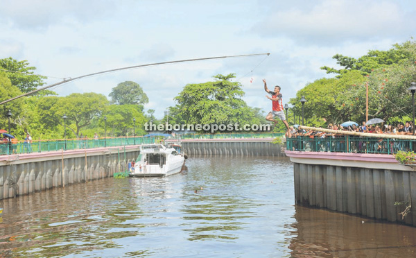 A contender leaps high into the air to grab the red packet dangled on a pole, before plunging hard into Seduan River.