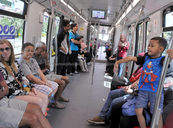 Members of the public using the driverless train during the first day of operations. — Bernama photo