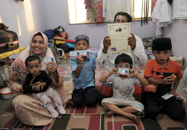 Aminah Asadullah (left), 38, with her husband and children showing their UNHCR card at the Rohingya settlement in Pasar Besar Selayang. — Bernama photo