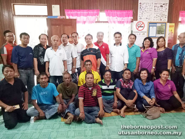 Bayang (standing fifth right) in a group photo with Rumah Enggul Village Security and Development Committee (JKKK) members. 