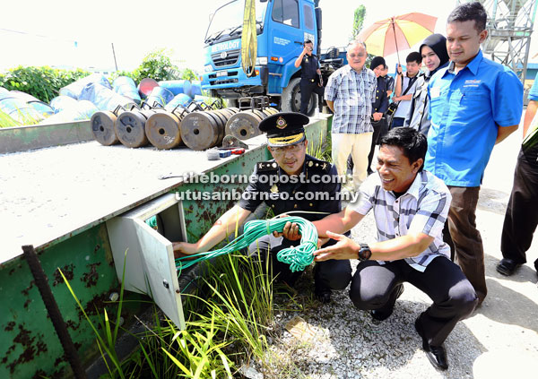 Hafidz (left) checking one of the electrical meters used for the vehicle weighing scales at one of the premises at Batu Kitang yesterday. — Photo by Muhammad Rais Sanusi