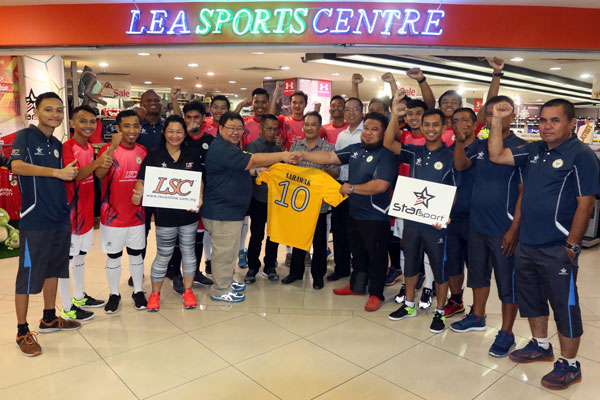 Poh (fifth left) handing the sponsorship to the Sarawak Futsal team in front of Lea Sports Centre in Sarawak Plaza yesterday. — Photo by Jeffery Mostapa