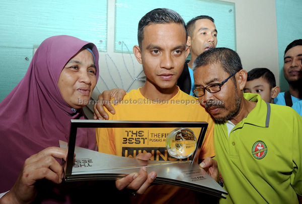 Faiz (centre) showing his Puskas 2016 trophy which he received at the FIFA Award ceremony in Zurich, Switzerland to both his parents Subri Kader (right) and Sadiah Ishak at Penang International Airport. Subri was the first football player from Asia to receive this prestigious award. — Bernama photo