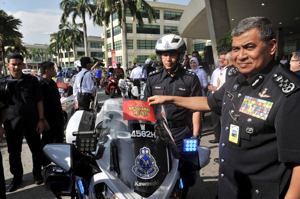 Khalid (right) putting a safety sticker onto a police motorcycle at the launch of Ops Selamat. — Bernama photo