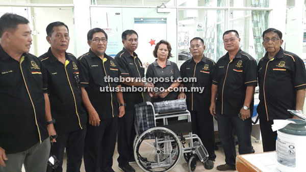 Melintang (fourth left) presents the wheelchair to Gu’s wife Jari Dadu at SGH, witnessed by other PVTKR members.
