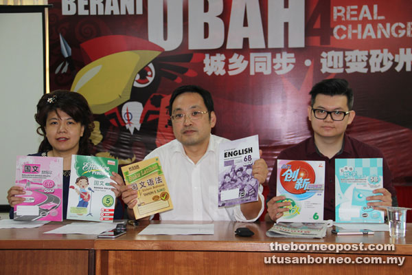 Chong (centre) highlighting the price differences between West and East Malaysia for activity books and workbooks used in primary schools, flanked by Yong (left) and Yii.