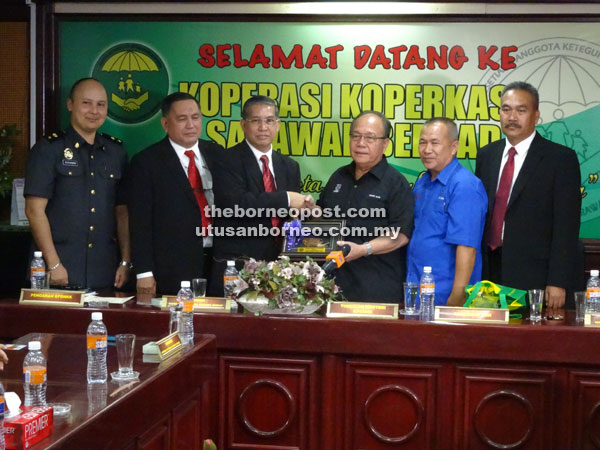 Sajali (third left) presenting a souvenir to Henry after a briefing session during a working visit to the Koperkasa Sarawak office. 