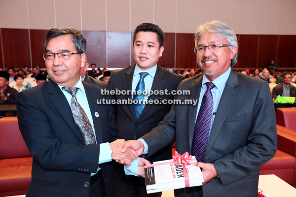 Mohd Yusof (left) presenting a souvenir to Samat as Tan looks on.   