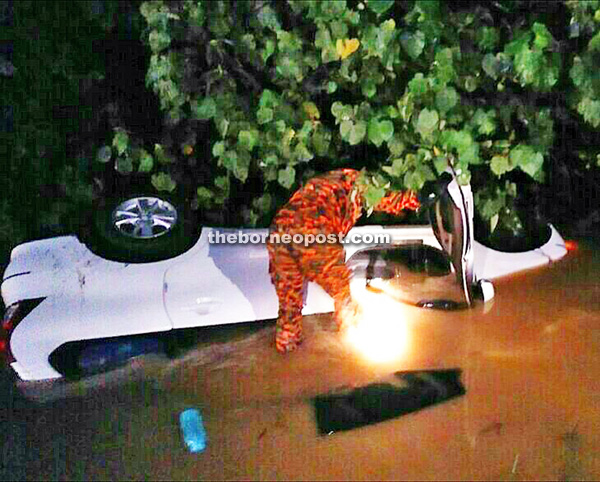 A fireman checking on the MPV, which landed in a ditch.