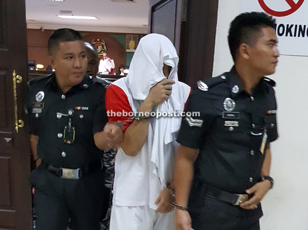 Chan being led by two Prisons Department officers from the courtroom.