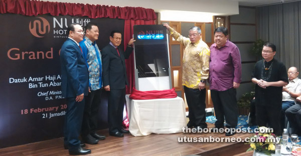 Lee and Tiong (third and fourth left, respectively) jointly unveil the banner board to mark the grand opening of Nu Hotel Bintulu.