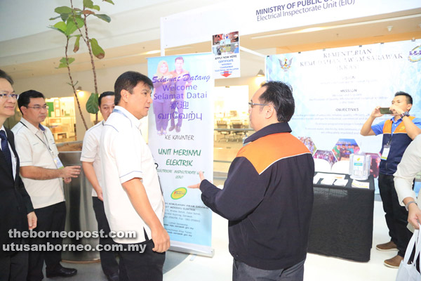 Sharbini (left) visits the exhibition booth of the Electrical Inspectorate Unit of the Ministry of Public Utilities.