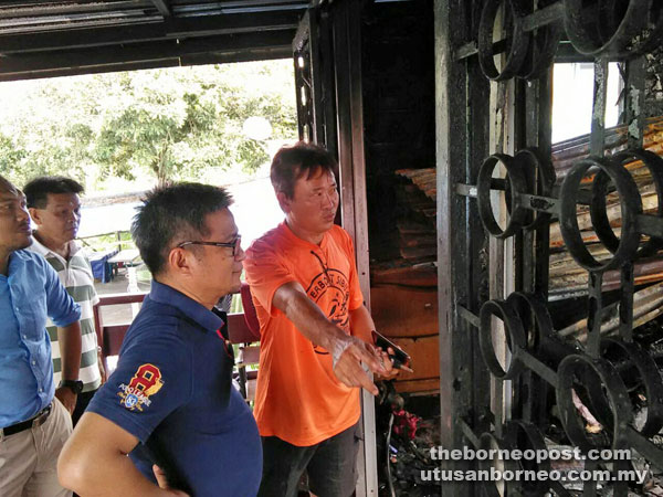 A victim (right) briefs Dr Annuar (second right) on the damage after the fire. 