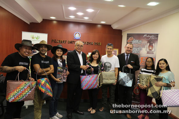 Tan (centre) presents a basket as a memento to Yii as Mark (left) and his team, representatives of Parkcity Everly Hotel and members of Helping Hands look on. 