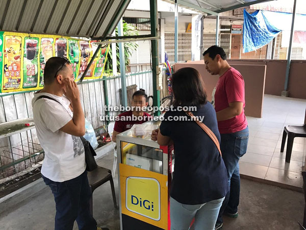 Police personnel confront the unlicensed lottery vendor at his kiosk.