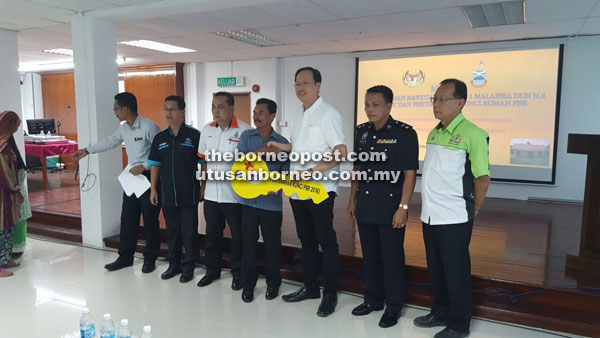 Teo (third right) presenting a mock key to one of the 37 recipients of PPRT houses.