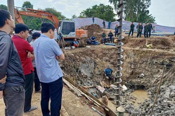 Des sauveteurs vietnamiens tentent de soulever un pilier en béton avec un garçon pris au piège